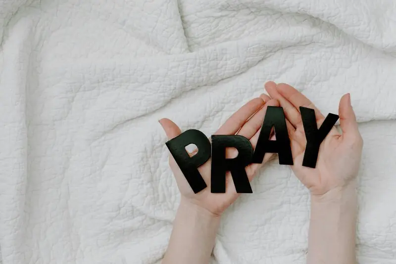 Hands holding the word PRAY for the CBTC weekly prayer line